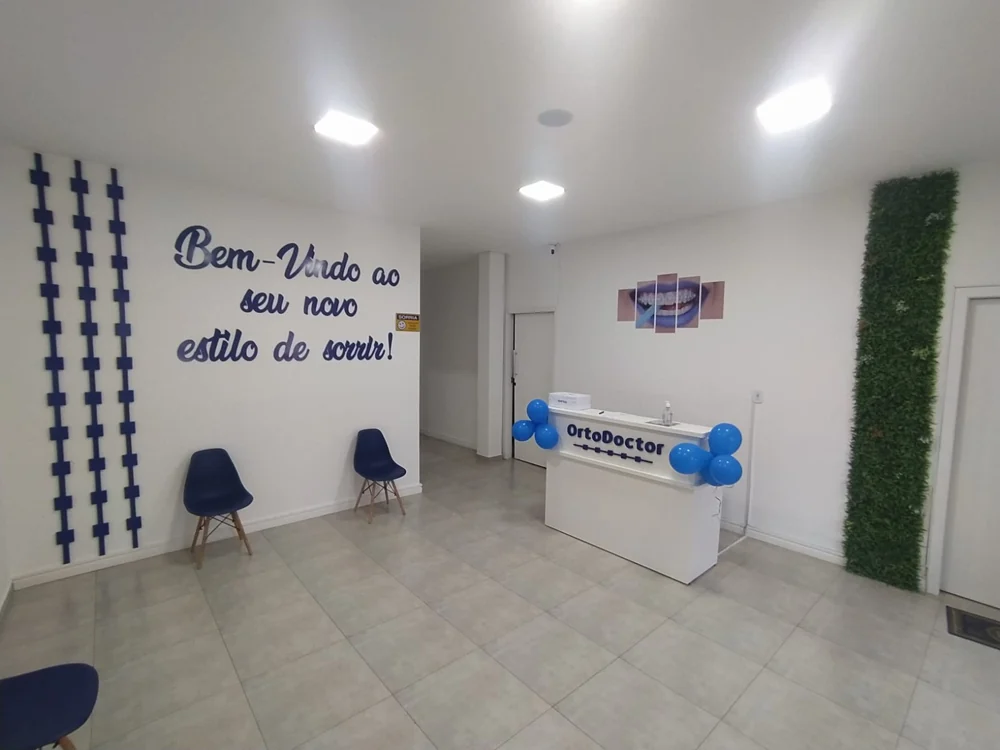 Recepção da Ortodoctor Vila A, com cadeiras azuis e a mensagem Bem-vindo ao seu novo estilo de sorrir